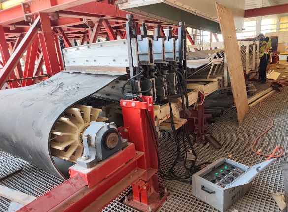 Presse hydraulique rouge avec flexibles près d'un palier, bande enroulée sur un tambour