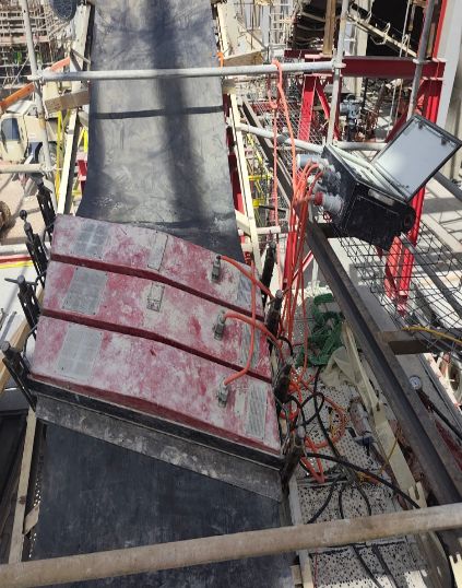 Presse de vulcanisation hydraulique rouge serrée sur une bande transporteuse inclinée